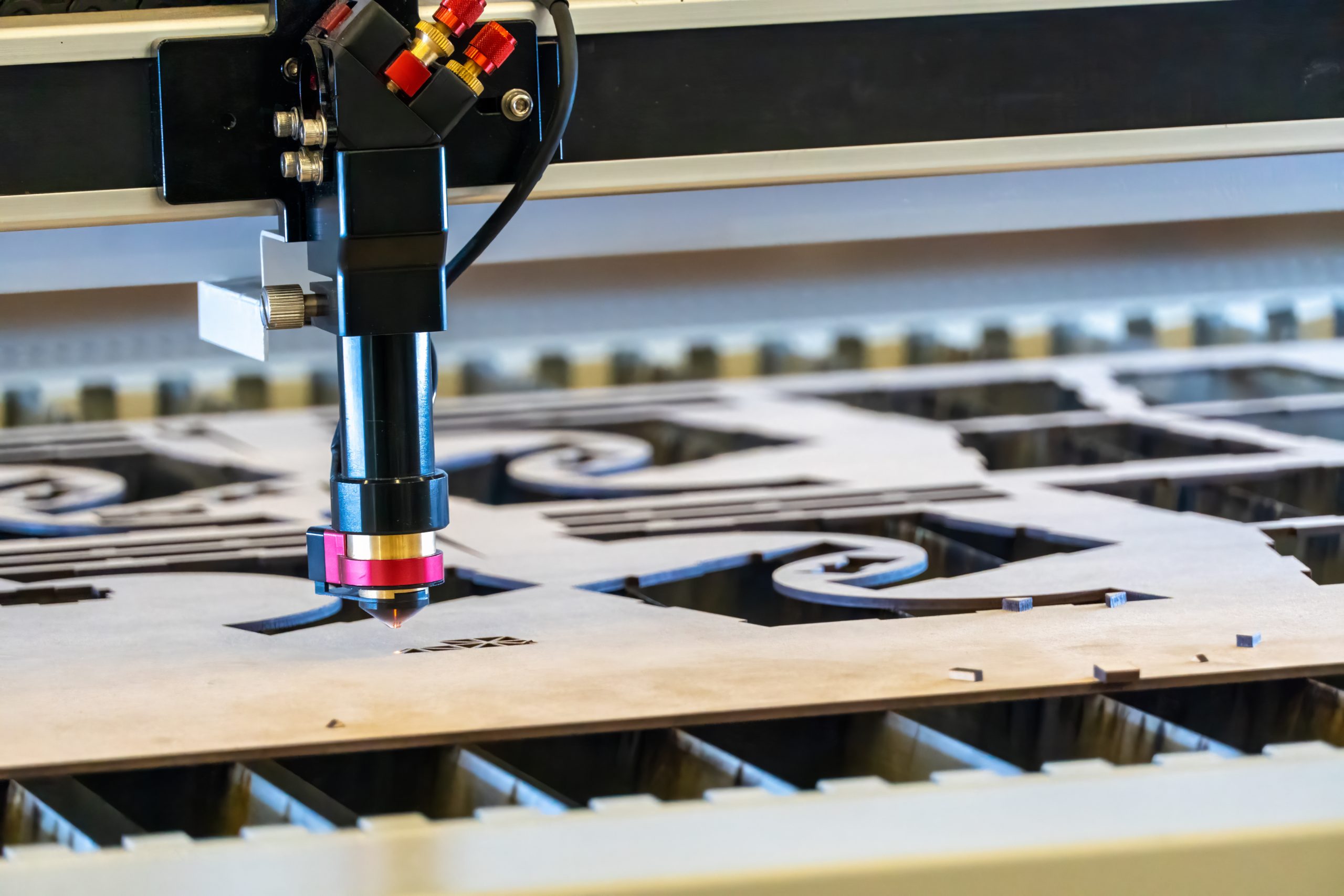 laser cutting machine, cutting wood sheets, while a man takes care of the process, latin america